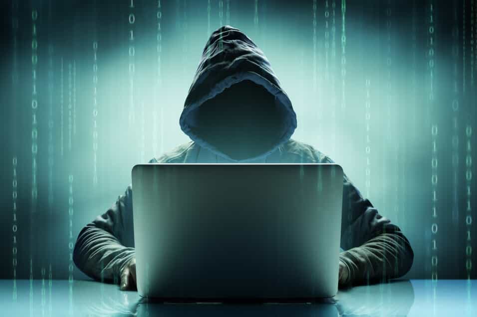 Hooded Figure Behind Laptop